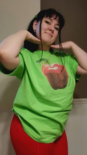 Reviewer smiling while wearing the vibrant green rotten classic tee with red leggings.