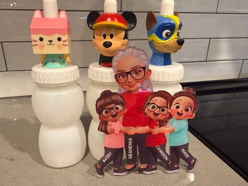 Customer's personalized acrylic magnet showing a grandma character hugging three grandkids, displayed on a counter.