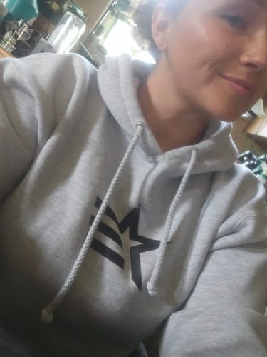 Reviewer smiling while wearing the gray fleece hoodie from the Lifestyle Bundle.