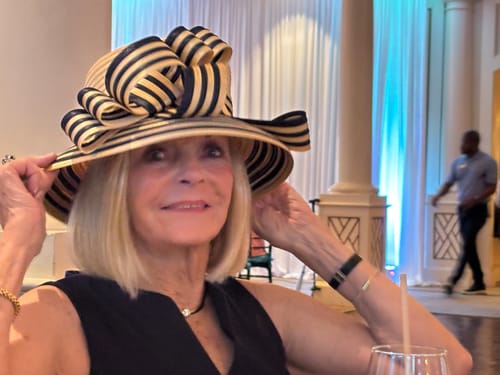 A smiling reviewer of Koriderm™ Time Reverse Cream, wearing a stylish striped hat.