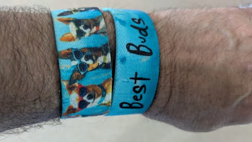 Customer's wrist wearing two blue Best Buds Dog Bracelets, one with a dog pattern and the other with the words "Best Buds".