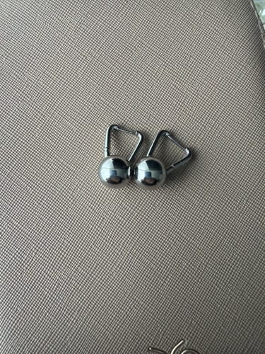 Customer's pair of Silver Dumbbell Hoop Earrings on a textured grey surface.