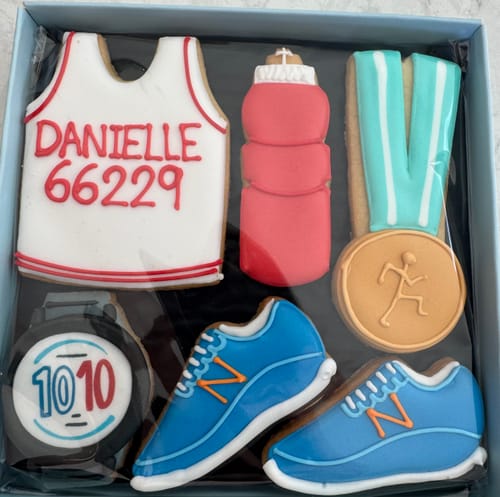Customer's Running Biscuit Box showing personalized biscuits shaped like a running vest, trainers, and a medal.