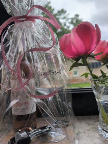 Rezensent zeigt das personalisierte Leonardo Weinglas in einer durchsichtigen Geschenkverpackung mit rosa Schleife.