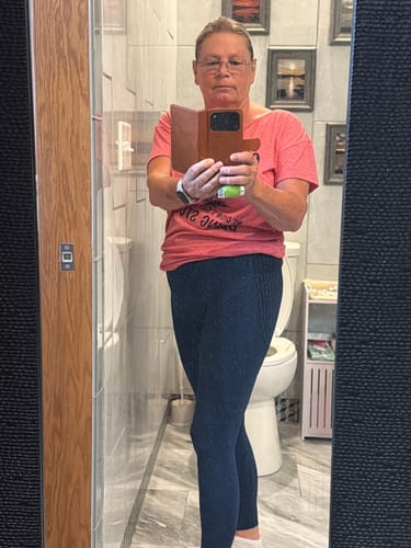 Reviewer showing the fit of the textured, dark blue 3D Anti-Cellulite Leggings in a mirror.