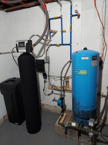 Customer's installed SoftPro® Elite HE Water Softener system in a basement with blue plumbing pipes.