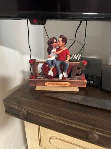 Customer's personalized 'LOVE' wooden plaque showing a kissing couple, displayed on a wooden dresser.