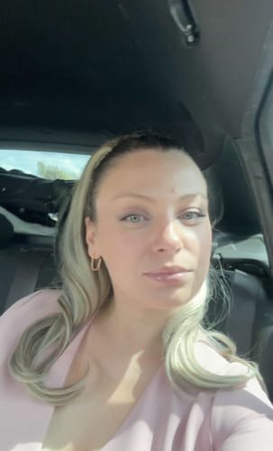 Customer wearing the wavy Ash Willow Blowout Clip-in Ponytail, with the hair falling over one shoulder.