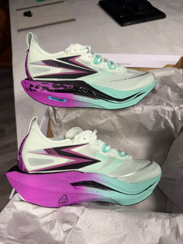 Reviewer's pair of Flame 5 "Apex" shoes with vibrant magenta and teal soles, sitting in the box.