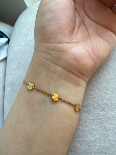 Customer's wrist wearing the gold Happiness Bracelet, showing its durable condition after four years of daily wear.