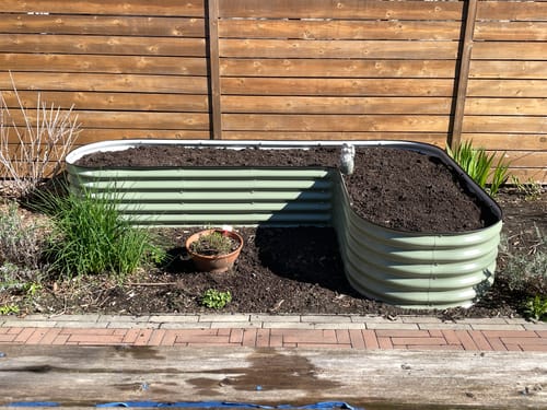 Customer's assembled 17” Tall L-Shape garden bed, filled with dark soil and a small garden gnome.