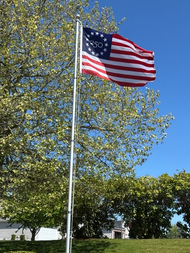 Customer's America 250™ Betsy Ross Flag waving on a flagpole outdoors on a sunny day.