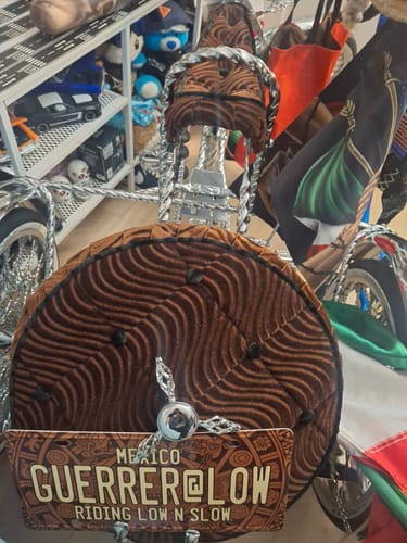 Customer's custom Aztec Calendar license plate with 'GUERRER@LOW' text, mounted on a brown lowrider tricycle.