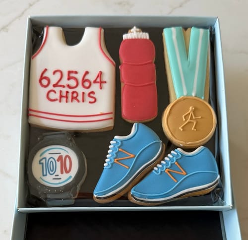 Customer's Running Biscuit Box with personalized biscuits shaped like a vest, trainers, medal, watch, and water bottle.
