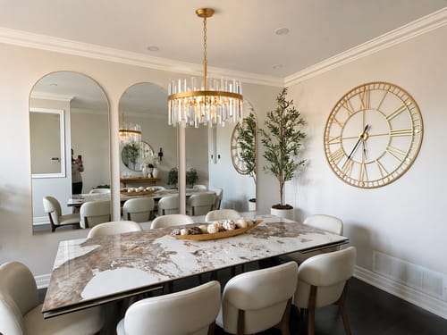 Customer's gold Roman numeral wall clock mounted in a dining room with a large table and arched mirrors.