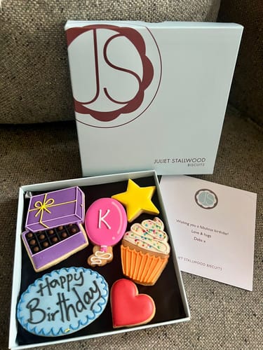 Customer's Celebration Biscuit Box opened to show colorful decorated biscuits, including a 'Happy Birthday' plaque and a cupcake.