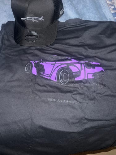 Customer's black DCG88 shirt with a purple car graphic, laid out with a matching black cap.