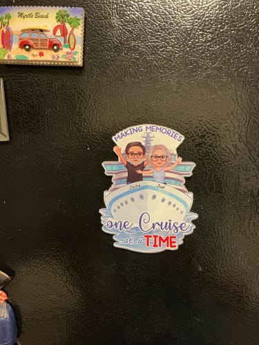 Customer's personalized cruise magnet with a happy couple illustration on a black refrigerator door.