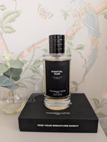 Reviewer's classy Santal Oud Eau de Parfum bottle standing on its black packaging box.