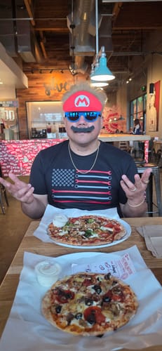 Reviewer wearing the black 80Eighty® Wrench Flag Shirt while sitting at a table in a restaurant.