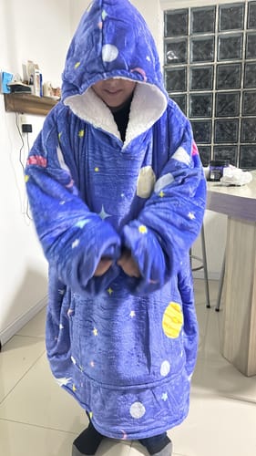 Cliente usando o cobertor vestível Sleepo, que é grande e azul com estampa de planetas.