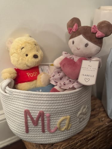 Reviewer's white personalized knitted basket with the name Mia and a flower icon, filled with stuffed toys.