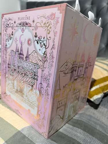 Customer's Manifest The Magic Makeup Set in its pink, fairytale-themed storybook packaging on a grey surface.