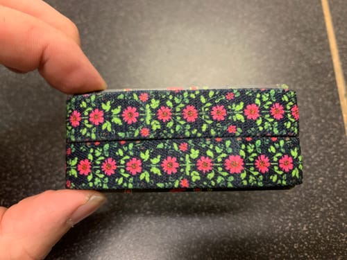 Customer holding the folded Root Down Rise Up Bracelet, showing its colorful floral pattern.