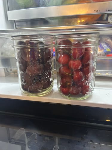Reviewer's two glass mason jars filled with fresh fruit, stored side-by-side in a refrigerator.