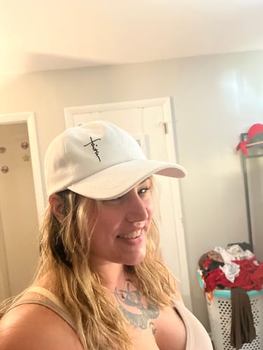 Reviewer smiling while wearing the white Ladies Ponytail Faith Hat indoors.