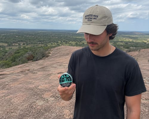 Reviewer looking at a can of Refreshing Chill Nicotine Pouches while standing on a rocky overlook.