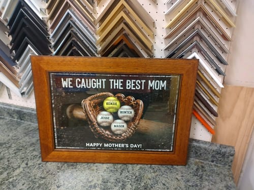 Customer's framed 'We Caught The Best Mom' personalized poster sitting on a counter in a frame shop.
