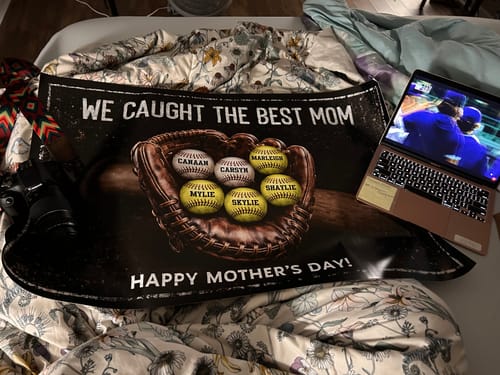 Customer's 'We Caught The Best Mom' personalized poster with six named baseballs in a glove, resting on a bed.