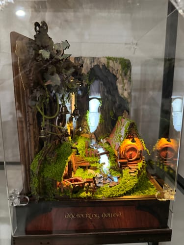 Customer's Whispering Hollow Miniature House Kit in a display case. The detailed scene has a lit house covered in moss.