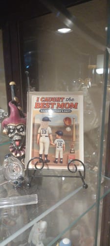 Customer's 'We Caught the Best Mom' acrylic plaque on a stand in a display cabinet.