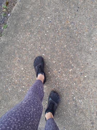 Customer's overhead view of their black Vitality III Barefoot Shoes while standing on pavement.