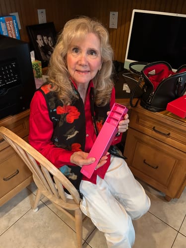 Reviewer smiling while holding her open pink Weekly Case at a desk.