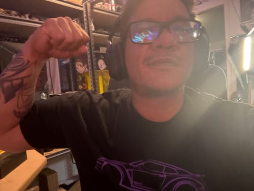 Customer flexing their arm while wearing the black 80Eighty® DCG88 Shirt with a purple graphic.