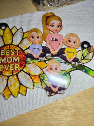 Customer's personalized sunflower suncatcher showing figures of a mom and three children sitting on a stem next to a large sunflower.