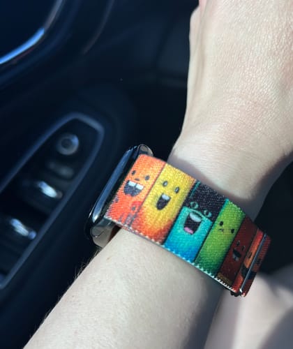Customer wearing the colorful 'Don't Judge A Book By It's Cover' watchband, showing cartoon books on their wrist.