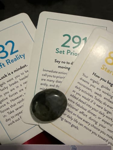 Reviewer's dark, polished monthly crystal displayed on top of several tarot cards.