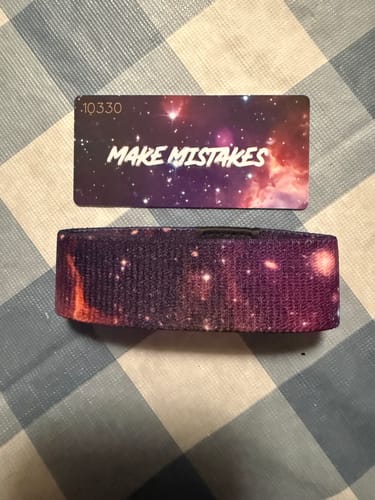 Customer's wristband from the mystery pack with a purple galaxy design and matching card reading 'MAKE MISTAKES'.