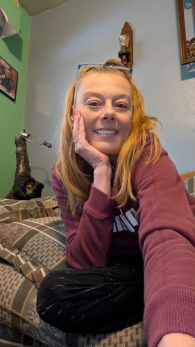 Customer smiling to show her bright Pop On Veneers while taking a selfie in a maroon sweatshirt.