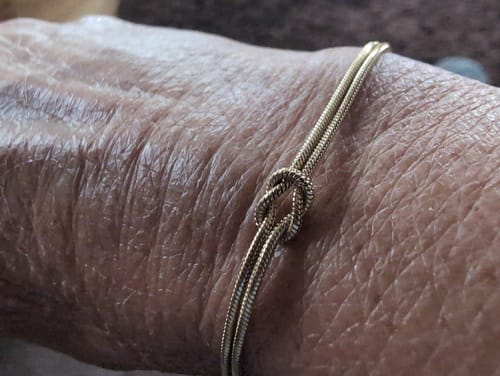 Close-up of a customer's wrist wearing the gold Forever Knot Bracelet.