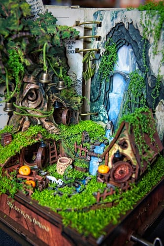 Customer's fully assembled Whispering Hollow Miniature House Kit, showing the intricate village with a waterfall and mossy details.