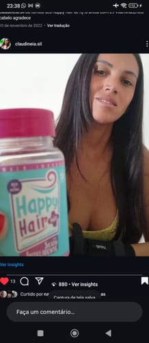 Cliente com cabelo escuro segurando um pote do suplemento Happy Hair.