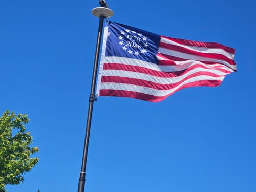 Customer's 1776 to 2026 Betsy Ross Flag flying on a flagpole against a clear blue sky.