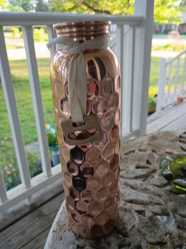 Customer's Diamond-Cut Honeycomb Copper Water Bottle sitting on an outdoor table.