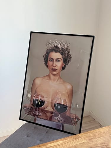 Customer's framed Majestic art print of a crowned woman holding a tray with two wine glasses, resting on a chair.