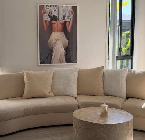 Customer's framed 'Made To Look V2' art print hanging on a wall above a curved, beige sofa.
